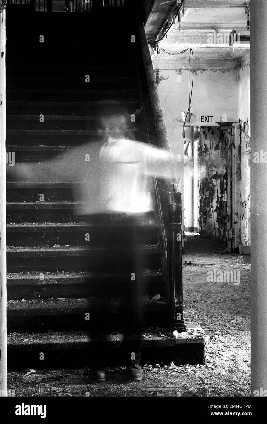 Uomo trasparente con braccia distese che si erge sulla scala dell'edificio abbandonato Foto Stock