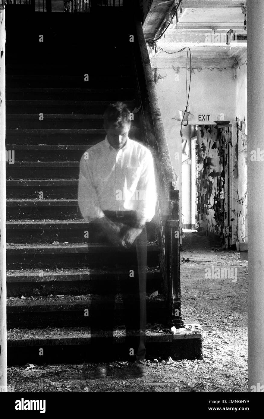 Uomo trasparente in piedi alla scala dell'edificio abbandonato Foto Stock