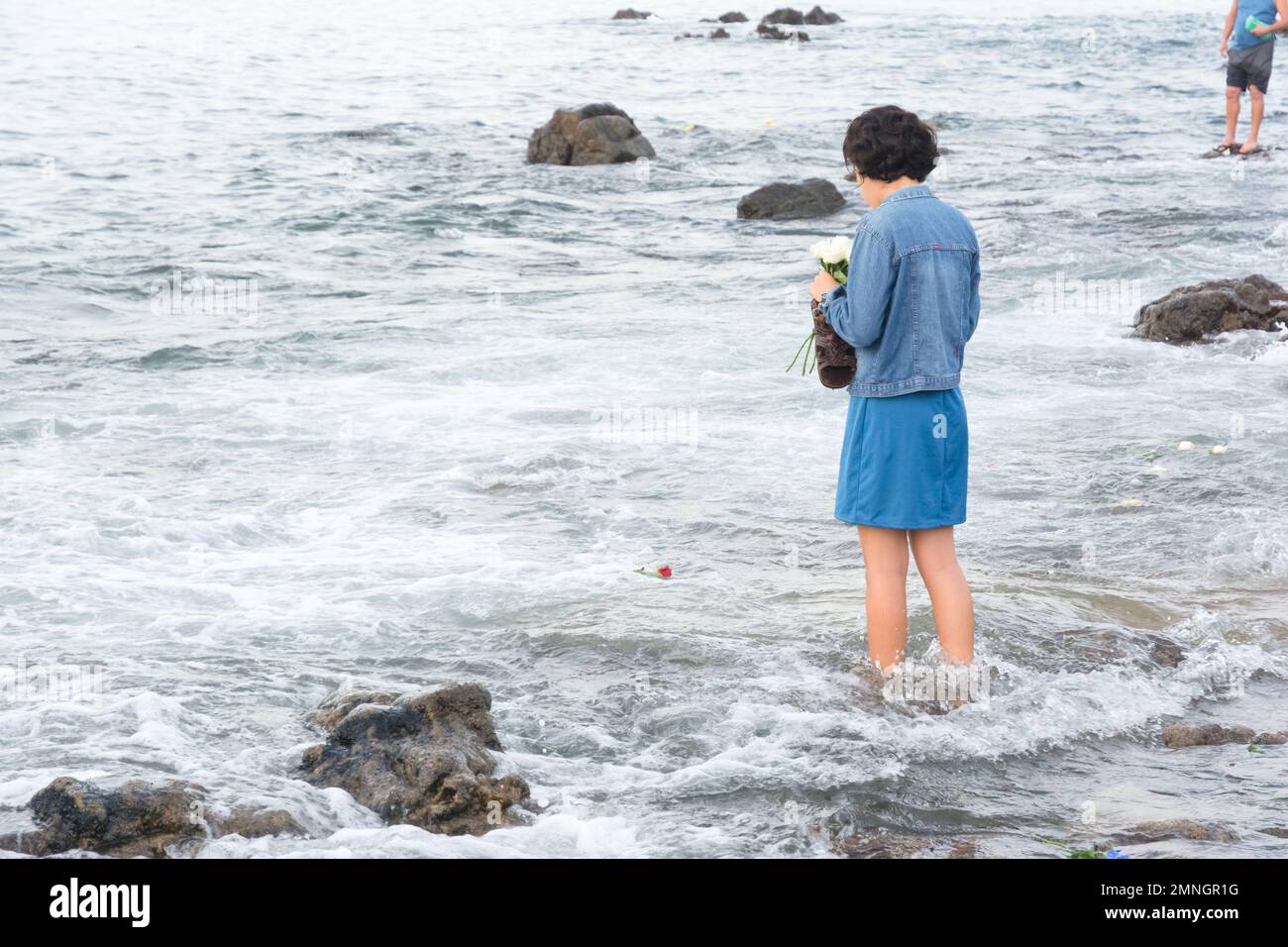Salvador, Bahia, Brasile - 02 febbraio 2017: Una donna che ammira Candomble getta fiori in mare in onore di Iemanja il giorno della sua festa. Salvador, Foto Stock