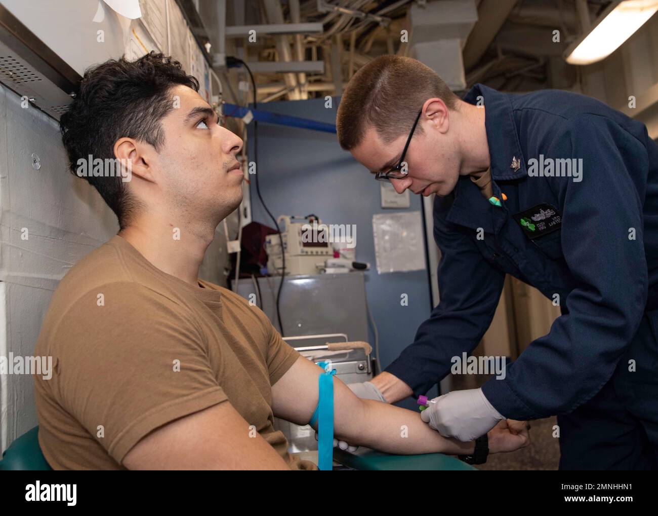 Un medico ospedaliero, assegnato al Fleet Surgical Team (FST) 4, preleva sangue da un tecnico dell'attrezzatura di supporto dell'aviazione 3rd Classe ca. 2020 Foto Stock