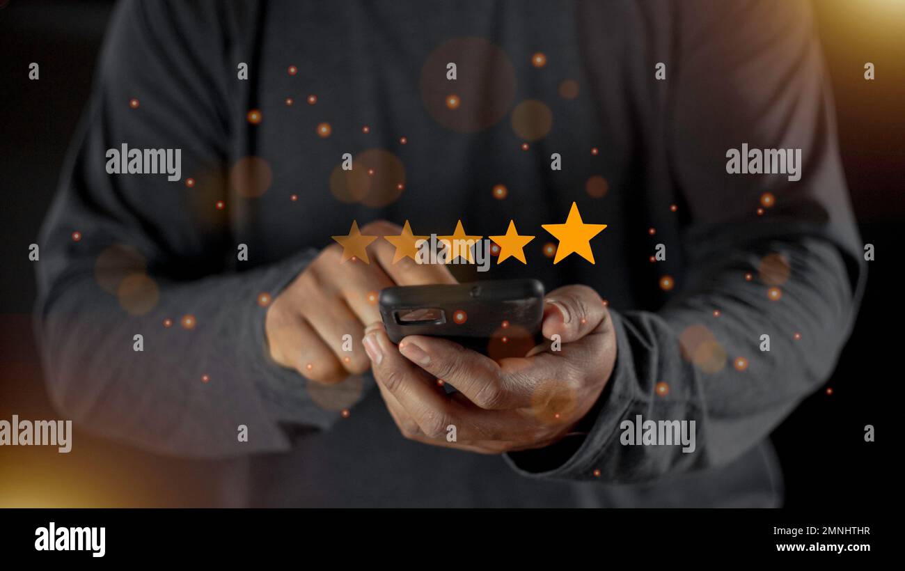 Soddisfazione primo piano sulla mano dell'uomo del cliente premendo sullo schermo con l'icona di feedback di valutazione a cinque stelle e il livello di pressione eccellente classifica per dare il miglior punteggio Foto Stock