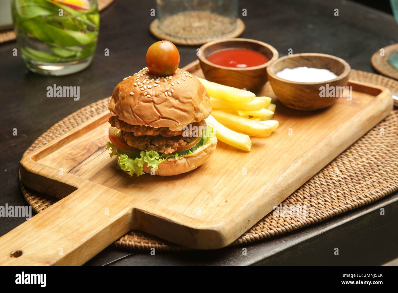 Hamburger di piccole dimensioni servito con patatine fritte e salse sulla tavola di legno nel caffè Foto Stock