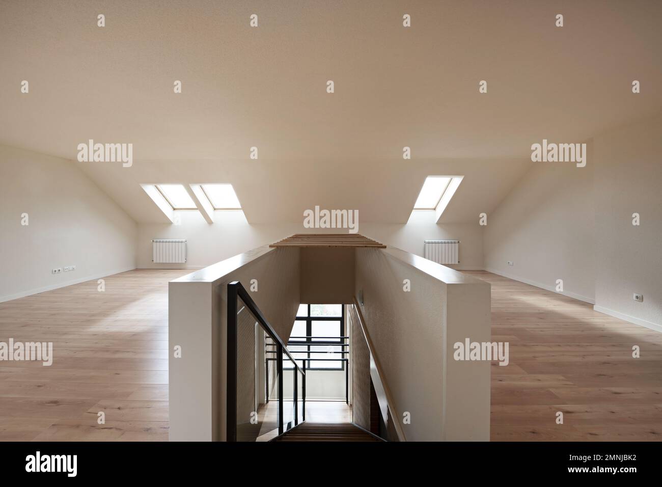 Mansarda vuota con pavimento in laminato di castagno, soffitti spioventi, lucernari e scale con ringhiera in metallo e vetro Foto Stock