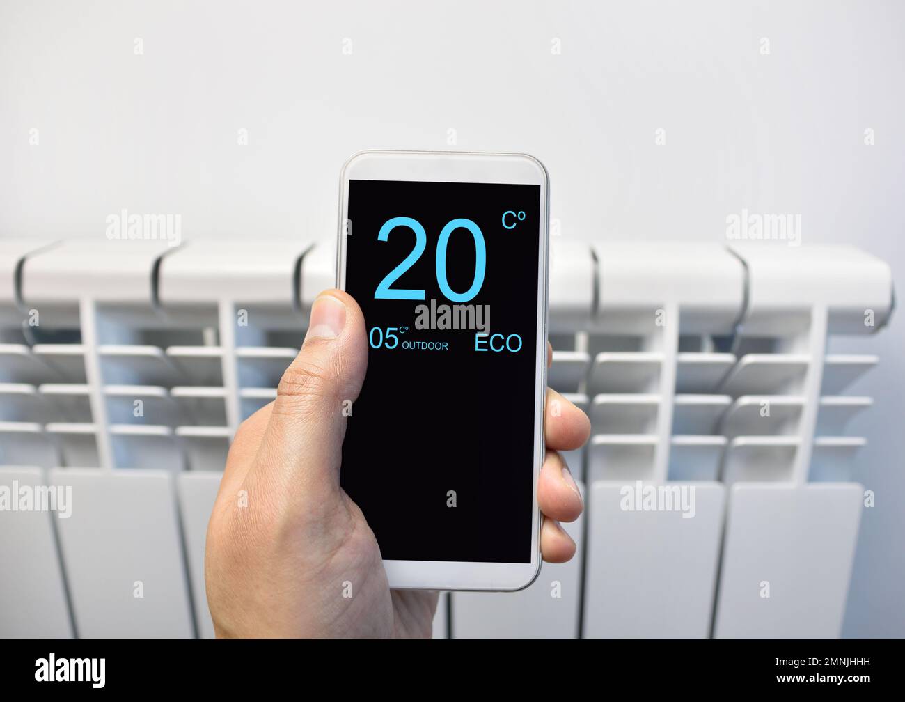 primo piano di una persona che regola la temperatura sul termostato tramite smartphone a casa Foto Stock