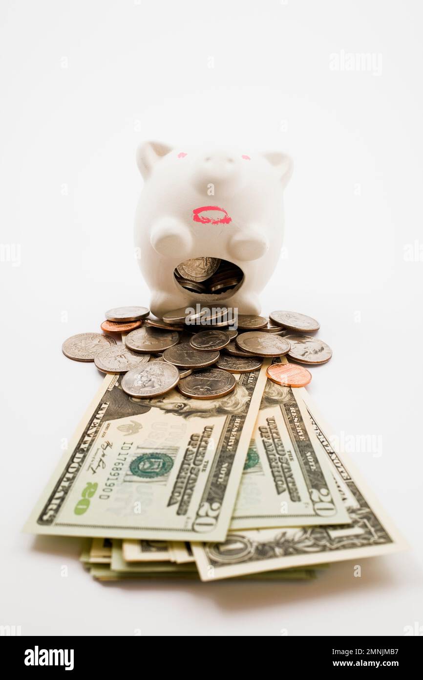 Salvadanaio che lancia monete statunitensi e banconote in valuta. Foto Stock