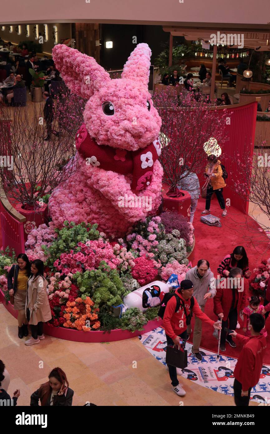 Gli amanti dello shopping si pongono di fronte all'esposizione "Year of the Rabbit" di Capodanno lunare, al centro commerciale Pacific Place, all'Ammiragliato, a Hong Kong, il 23 gennaio 2023 Foto Stock