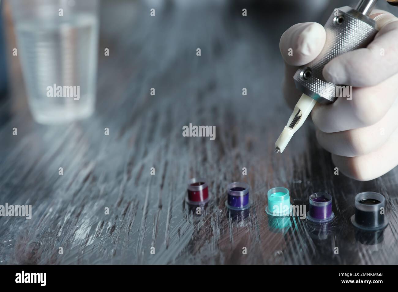 Artista tatuaggio con macchina e inchiostro a tavola, primo piano Foto Stock