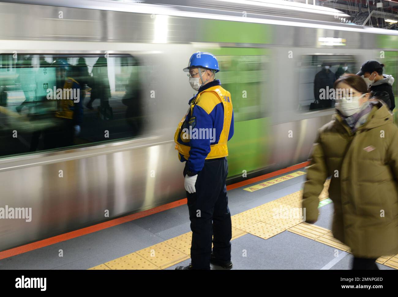 Lavoratore della sicurezza ferroviaria in piedi sulla piattaforma della linea JR Yamanote a Shibuya, Tokyo, Giappone. Foto Stock
