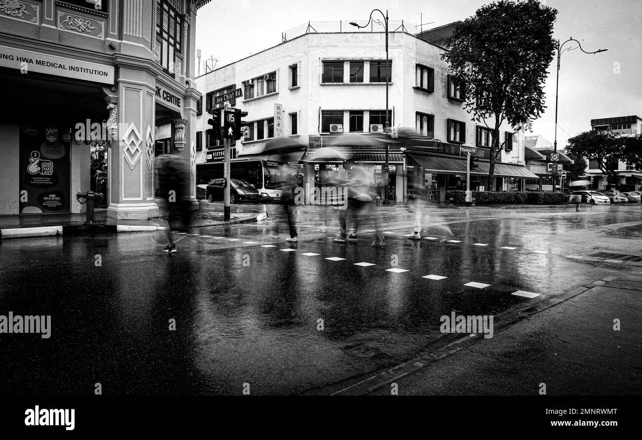 I pedoni camminano sotto i loro ombrelloni a Katong, Singapore Foto Stock