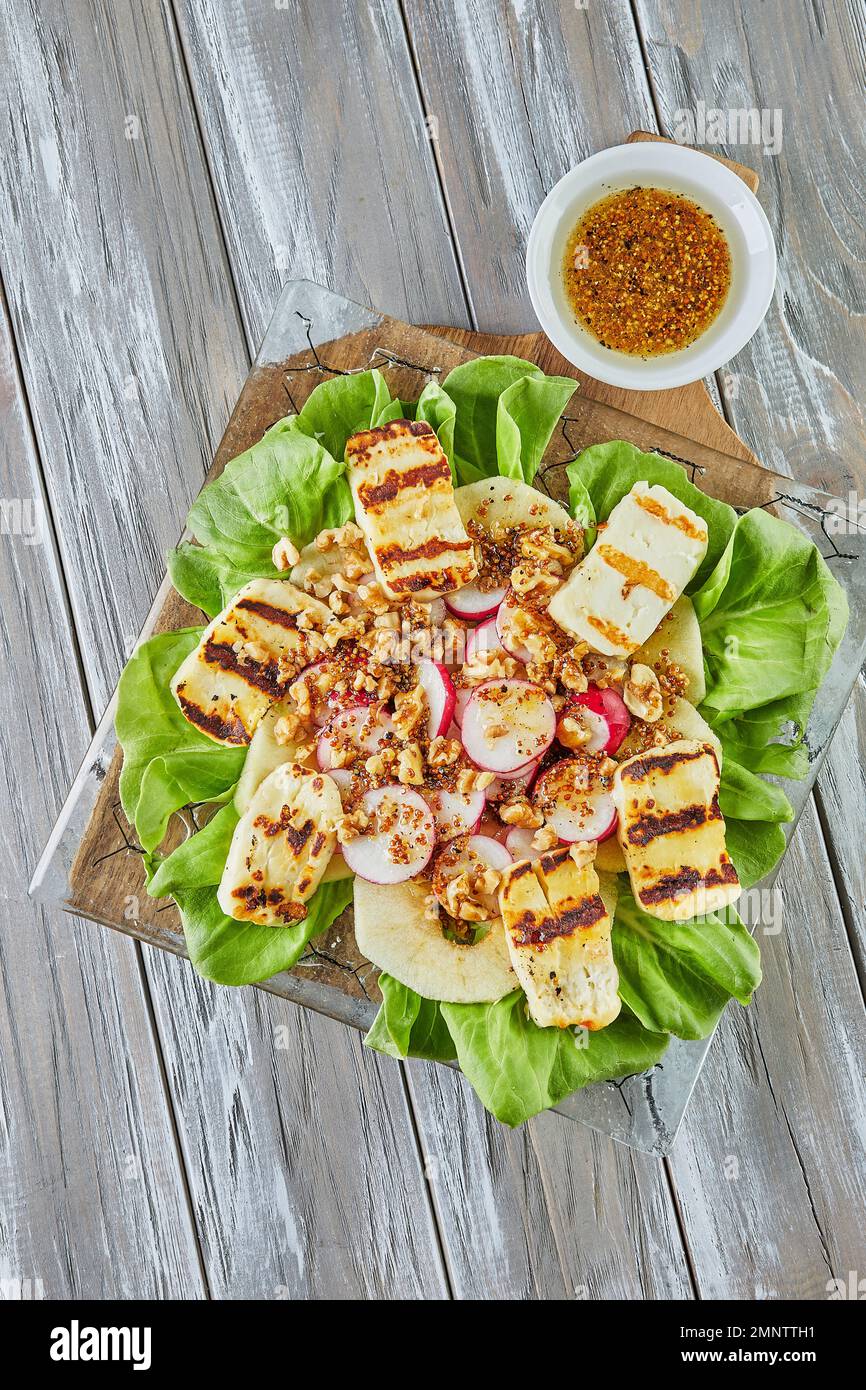 Insalata di mele, lattuga e formaggio halloumi su legno Foto Stock