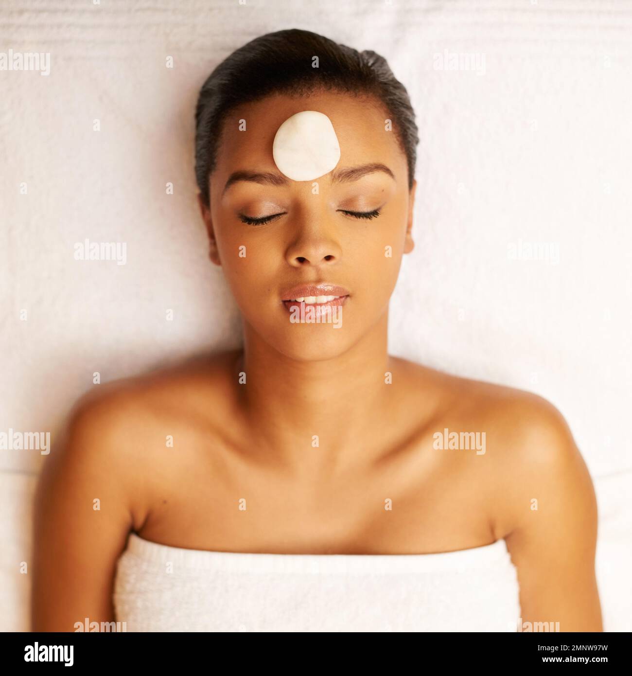 Ha dimenticato tutto del mondo esterno. una giovane donna che ama fare una terapia con lastone presso il centro benessere. Foto Stock