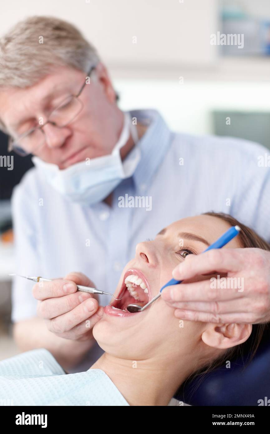 Per un sorriso migliore. Ritratto di medico maturo maschio che controlla i denti delle donne. Foto Stock