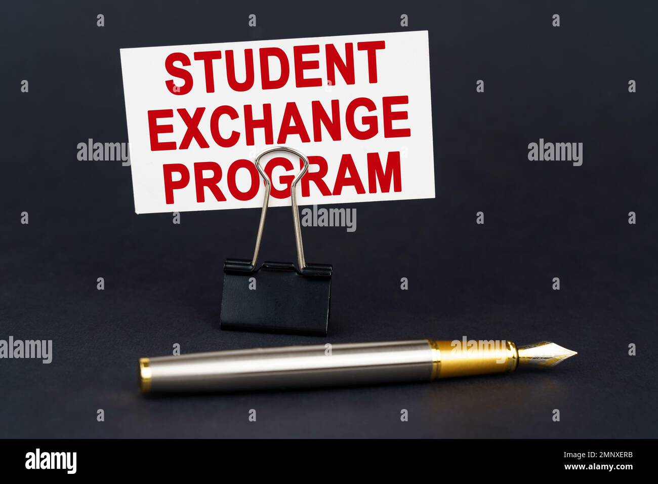 Concetto aziendale. Sulla superficie nera è presente una penna, una graffetta per ufficio con un biglietto da visita su cui è scritto - Student Exchange Program Foto Stock