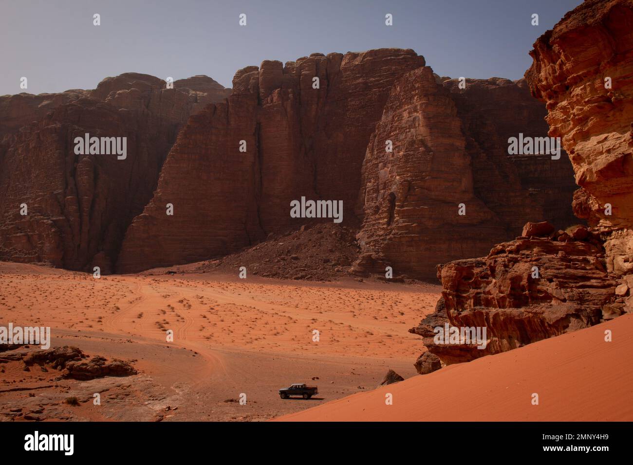 Un veicolo 4x4 di fronte a una delle maestose dune del deserto di Wadi Rum, Giordania Foto Stock