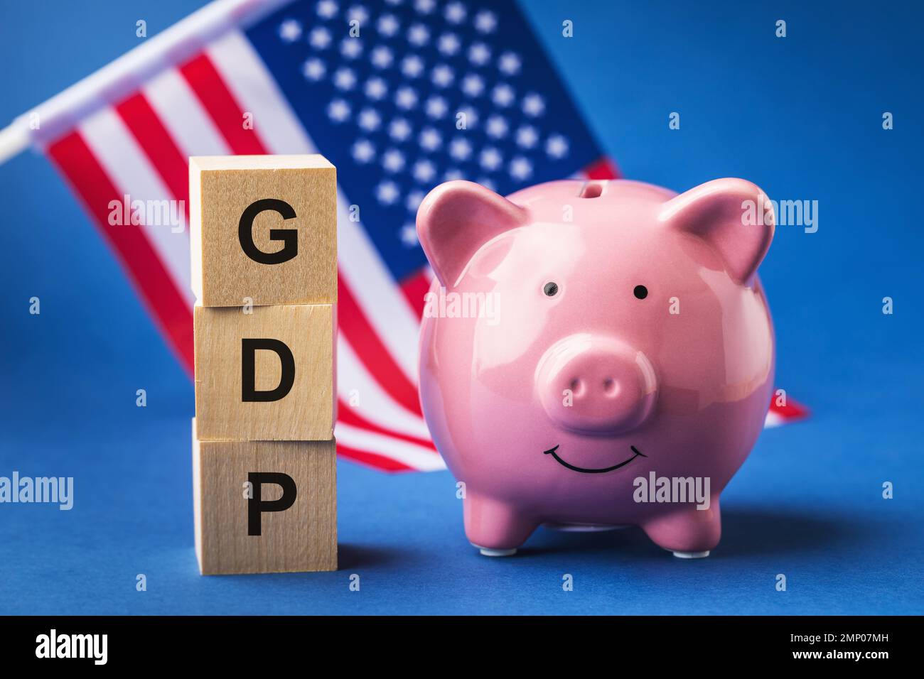Piggy bank, cubi di legno con testo e una bandiera su sfondo blu, un concetto sul tema del PIL degli Stati Uniti d'America Foto Stock
