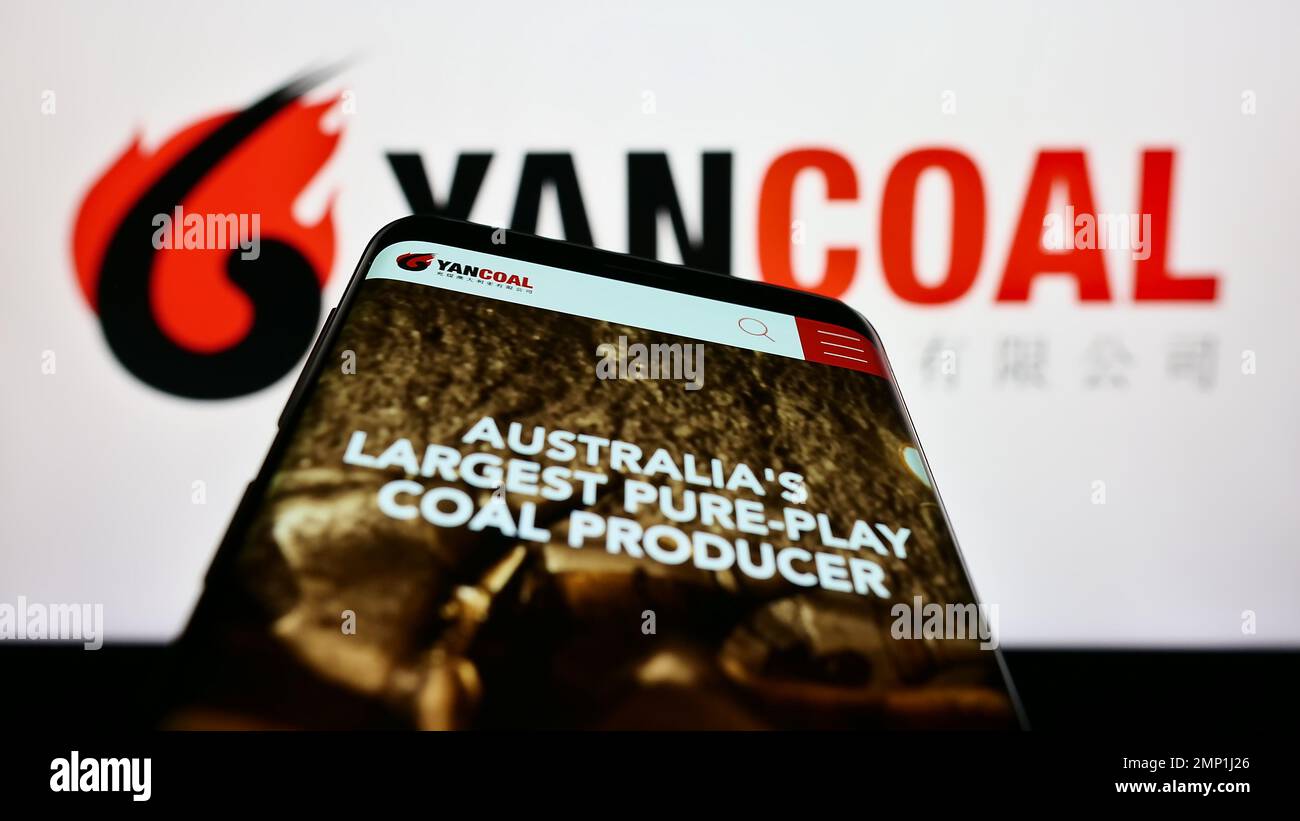 Telefono cellulare con sito web della società mineraria Yancoal Australia Limited sullo schermo di fronte al logo. Messa a fuoco in alto a sinistra del display del telefono. Foto Stock