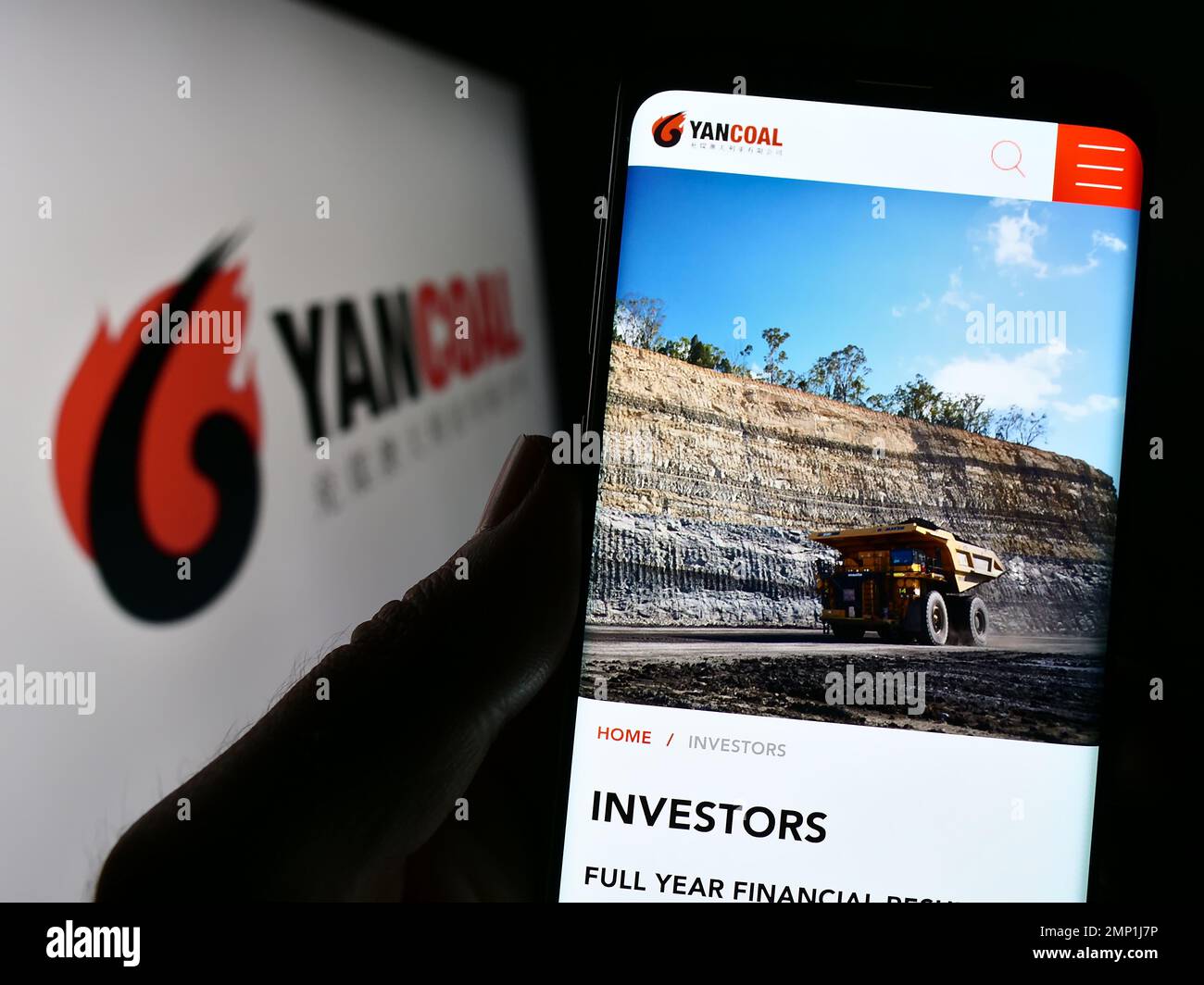 Persona in possesso di smartphone con pagina Web della società mineraria Yancoal Australia Limited sullo schermo con logo. Messa a fuoco al centro del display del telefono. Foto Stock