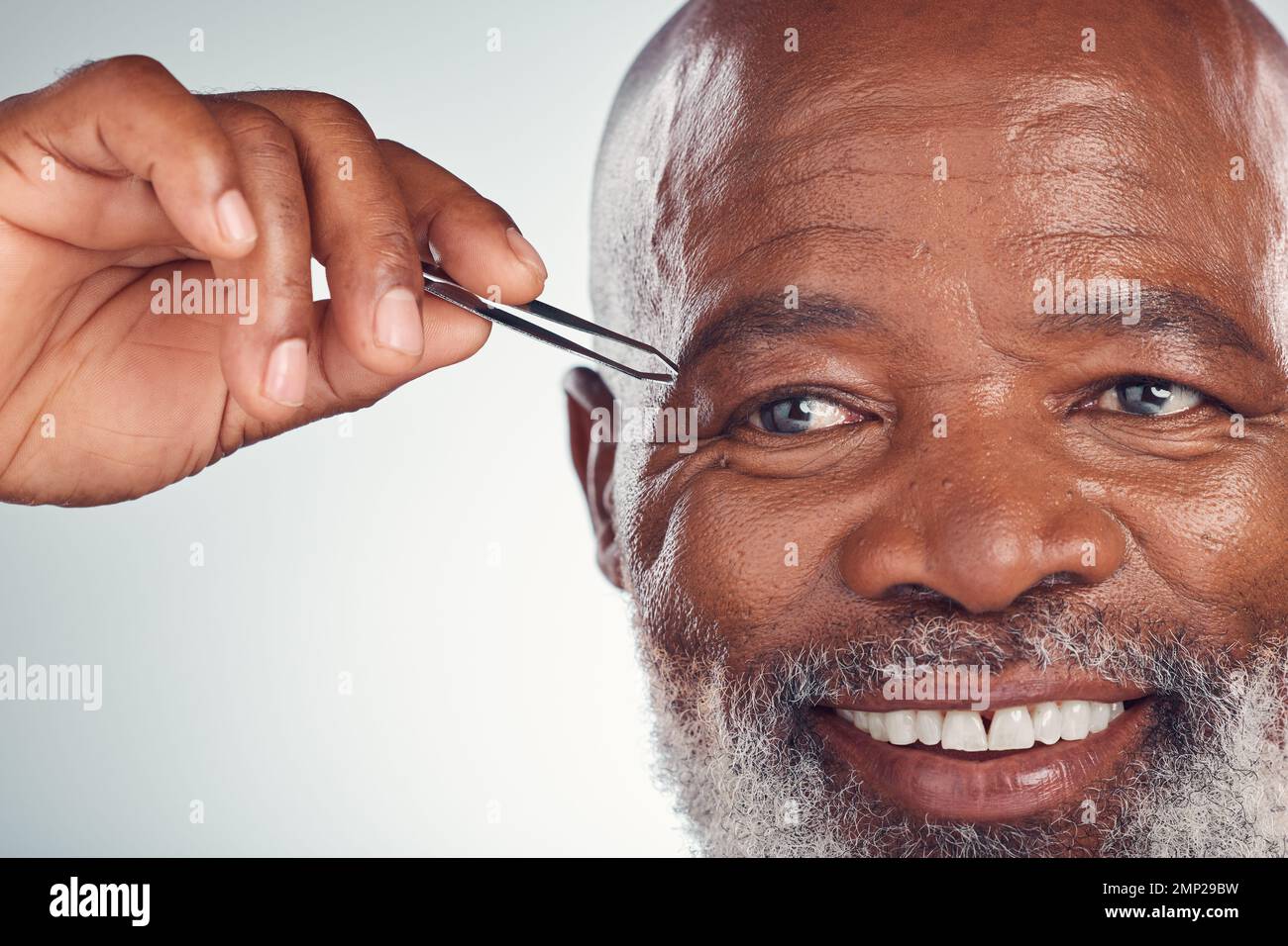 Governare, sorridere e uomo nero con pinzette per la rimozione dei capelli isolato su sfondo grigio studio. Pulizia, di routine e persona africana anziana con un Foto Stock