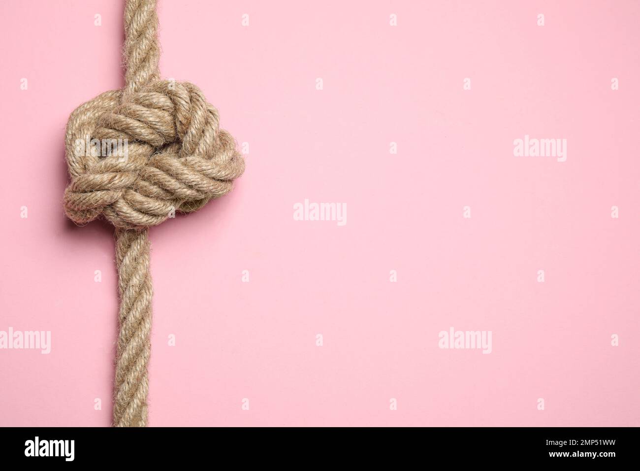 Vista dall'alto della corda di lino con nodo su sfondo rosa, spazio per il testo. Concetto di unità Foto Stock