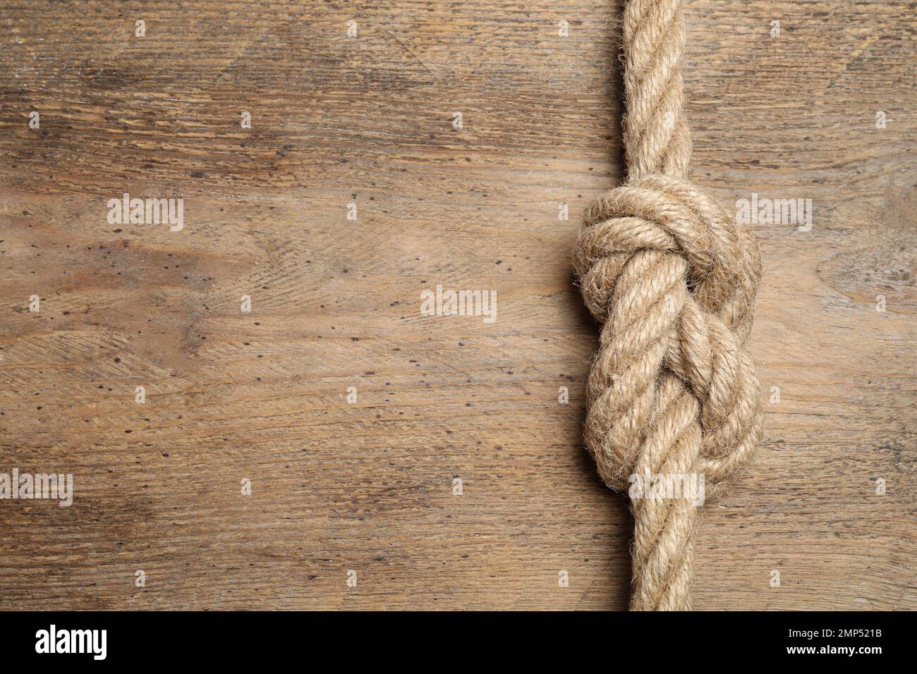 Vista dall'alto della corda di lino con nodo su sfondo di legno, spazio per il testo. Concetto di unità Foto Stock