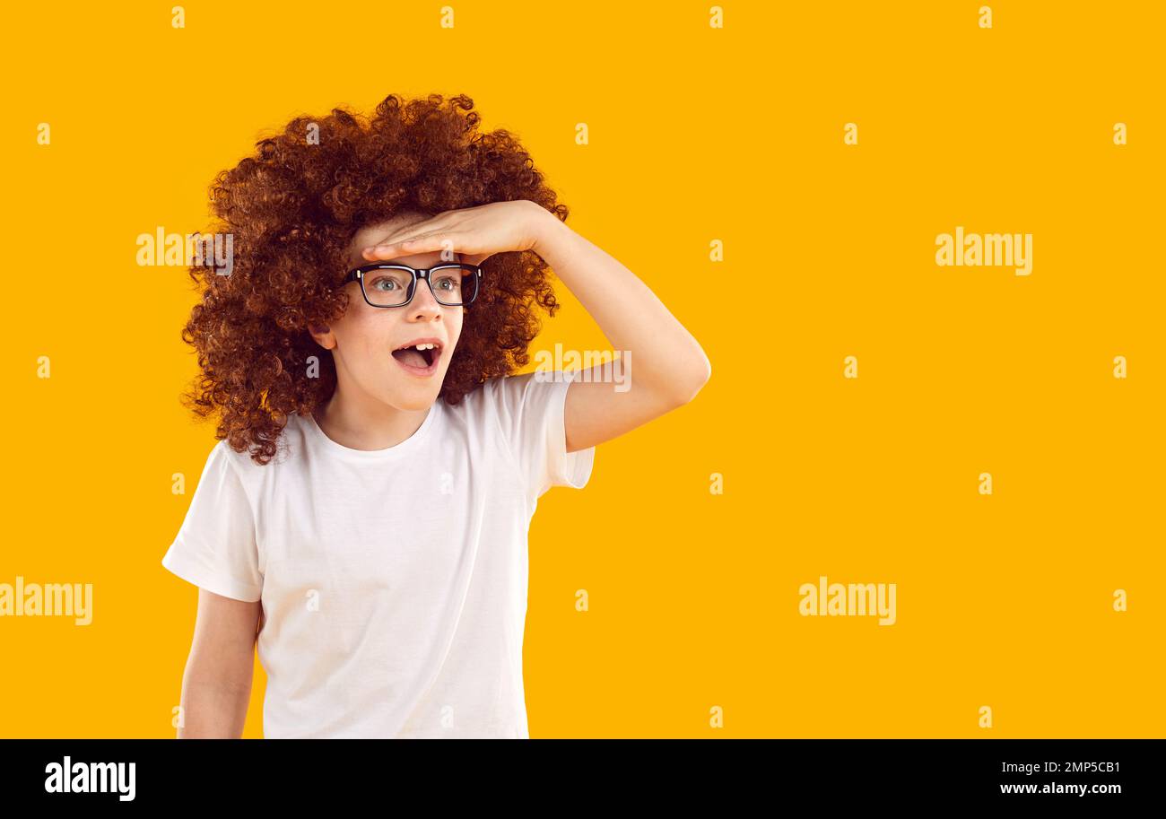 Ritratto di divertente, dentifricio, stupito adolescente in occhiali trasparenti e una parrucca riccio Foto Stock