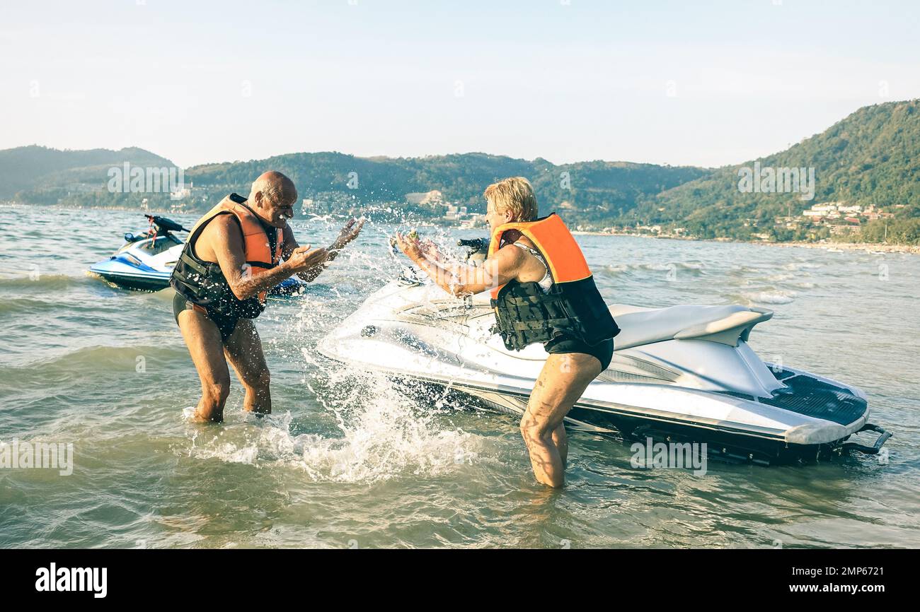 Coppia felice anziana che ha divertimento giocoso al jet ski sul giro dell'isola della spiaggia - concetto attivo di viaggio anziano intorno al mondo con la gente pensile Foto Stock