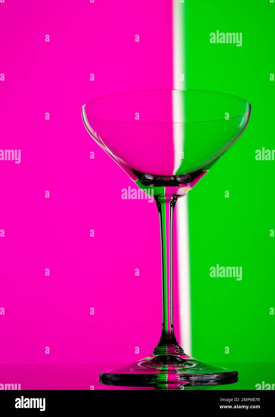 Cocktail party in vetro in colori al neon. Primo piano su sfondo colorato. Bicchiere di champagne moderno ed elegante. Foto Stock