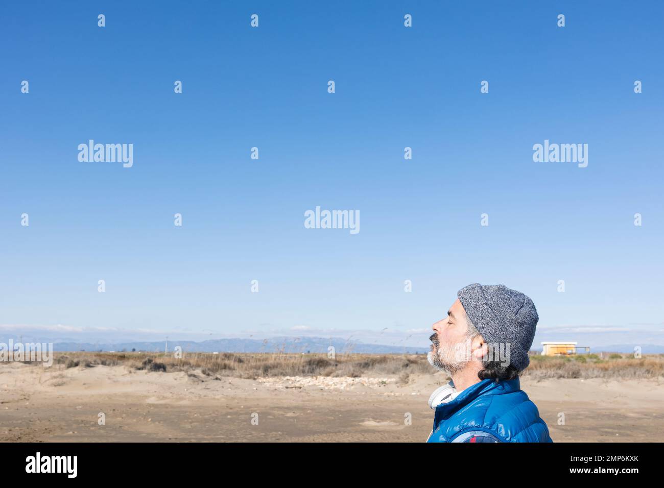 Uomo rilassato respirare aria fresca vicino alle montagne con un cielo blu sullo sfondo Foto Stock