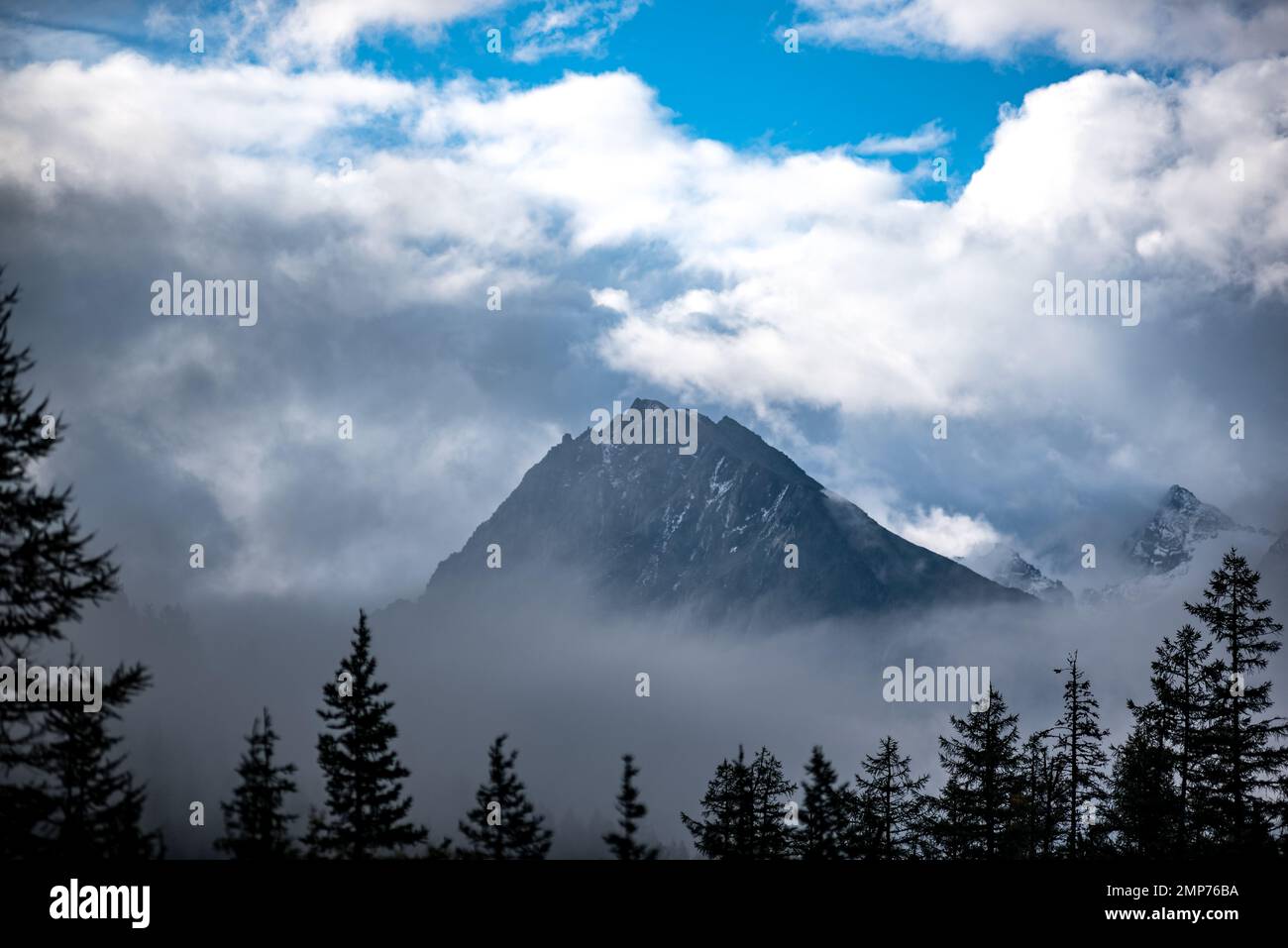 La cima di una montagna di pietra incorniciata da nebbia e nuvole bianche con ombre di abete rosso di alberi forestali in Altai. Foto Stock