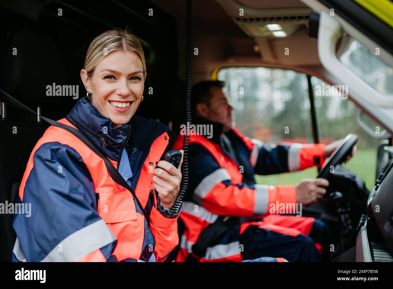 Ritratto di giovane donna medico seduta e parlare in walkie-talkie in auto ambulanza. Foto Stock