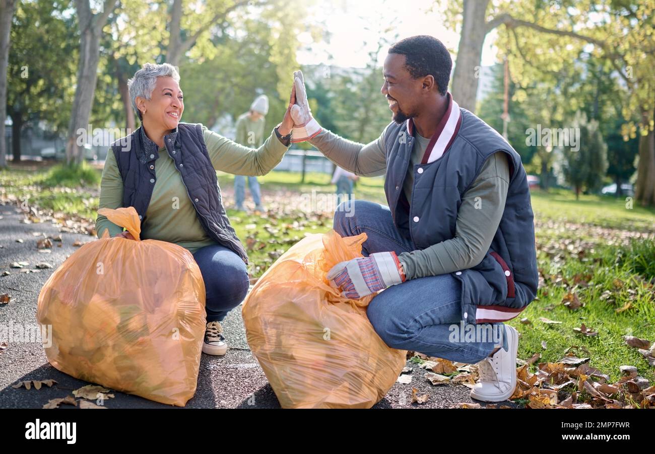 Alto cinque, volontario o squadra celebrare pulizia immondizia inquinamento, prodotto di scarto o supporto ambientale. Contenitore in sacchetto di plastica, aiuto di beneficenza ONG o. Foto Stock