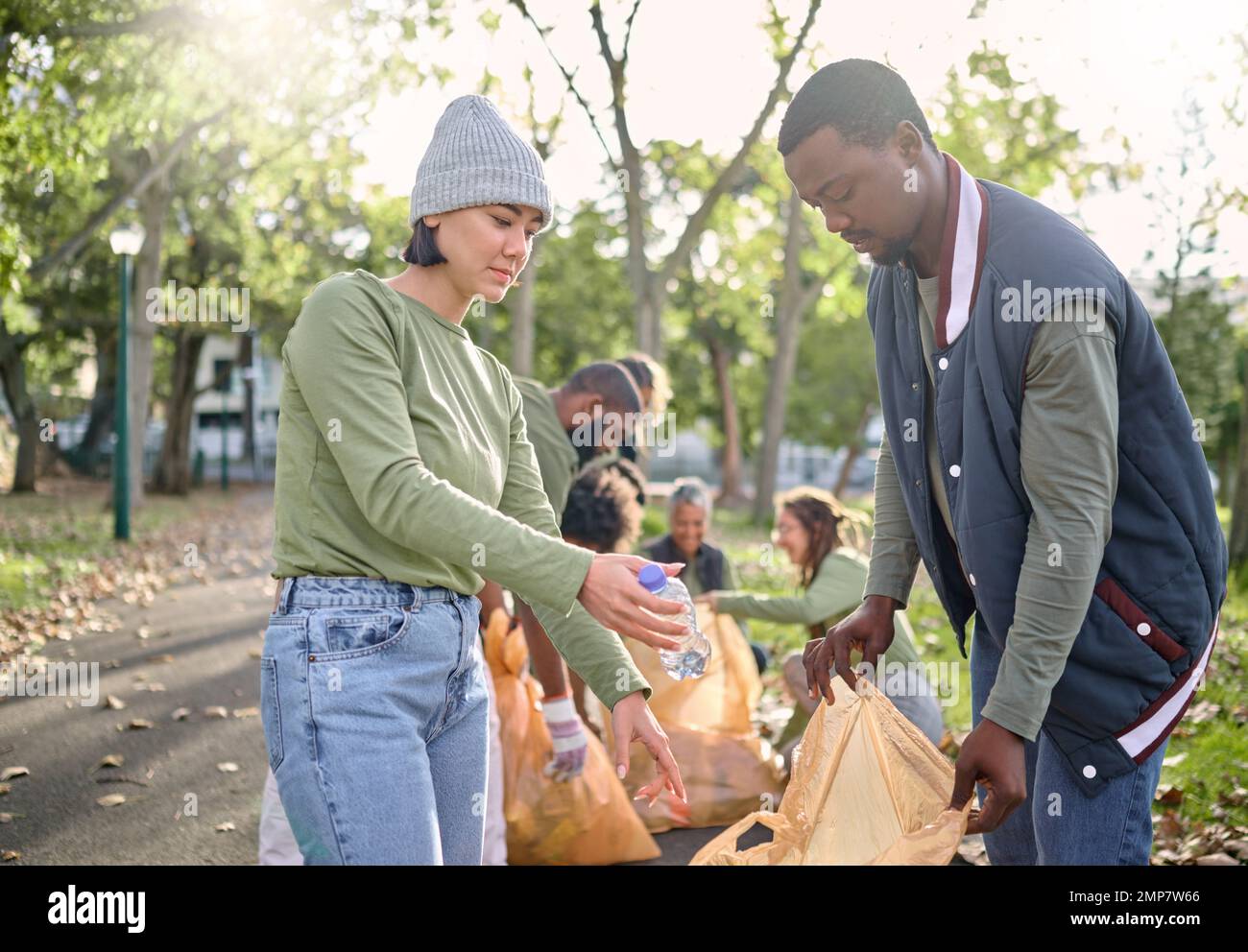 Volontariato, servizio di comunità e la gente di pulizia del parco con sacco per rifiuti per un ambiente pulito. Uomini e donne che aiutano con rifiuti o plastica per l'eco Foto Stock