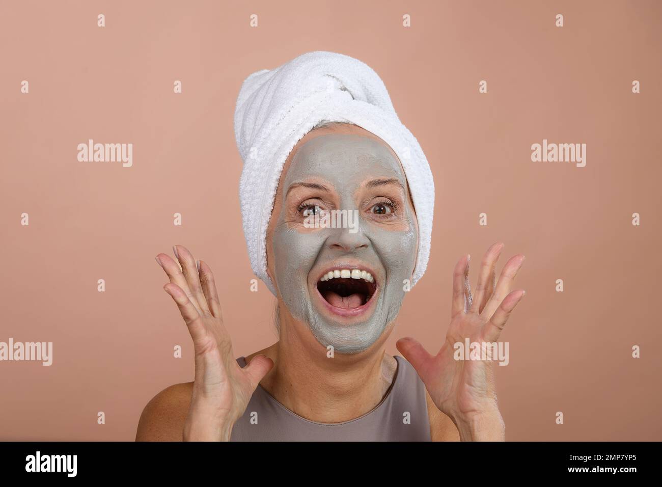 Ritratto di donna anziana eccitata con maschera facciale, auto-cura e concetto di routine della pelle. Foto Stock