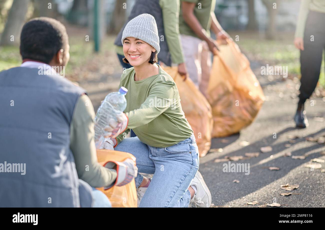 Volontariato, servizio di comunità e persone che puliscono la plastica nel parco con sacco per rifiuti. Felice donna e uomo squadra aiutare con spazzatura per uno stile di vita ecocompatibile Foto Stock