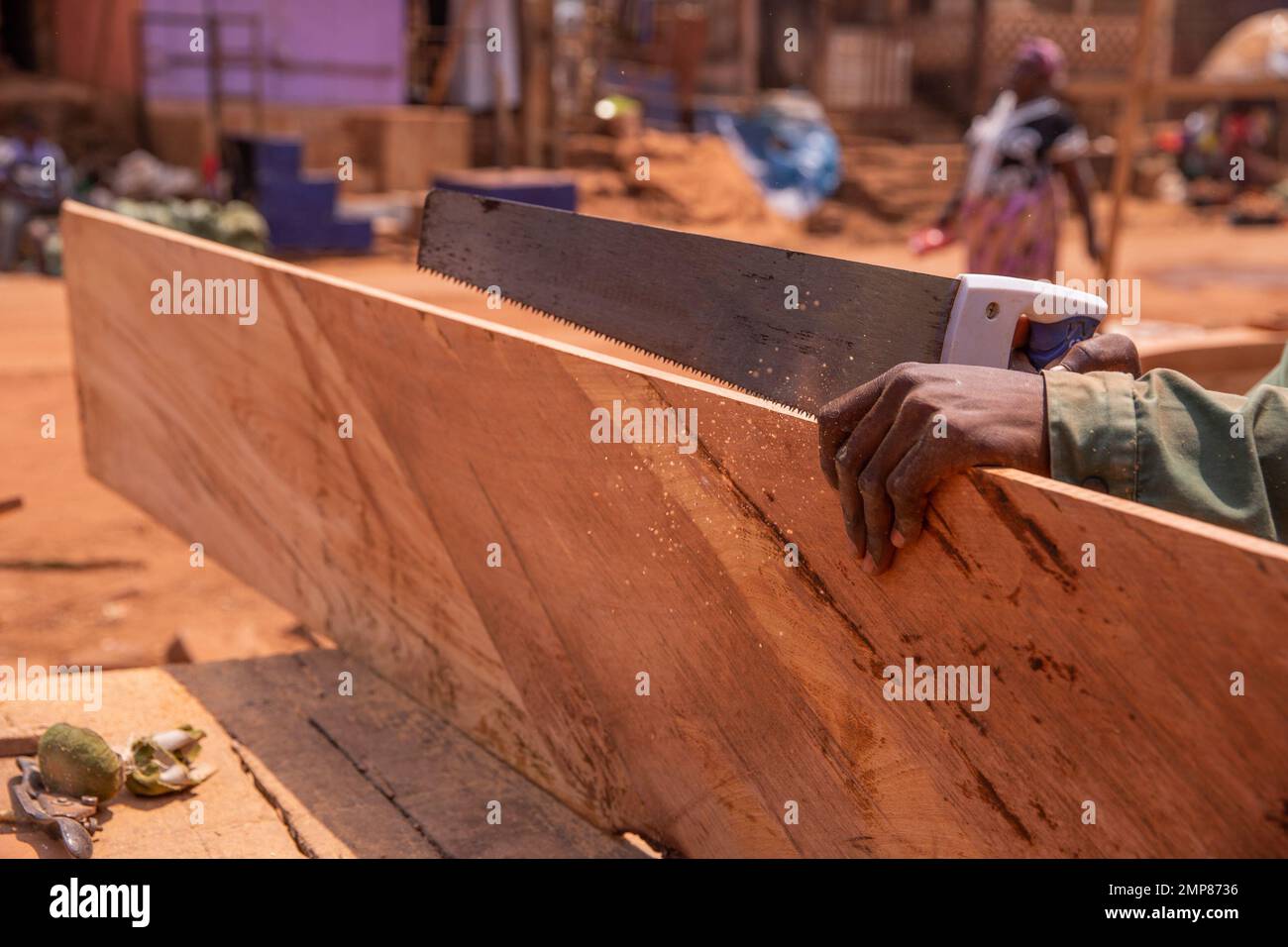 Primo piano delle mani di un falegname che taglia una tavola con la sega a mano Foto Stock