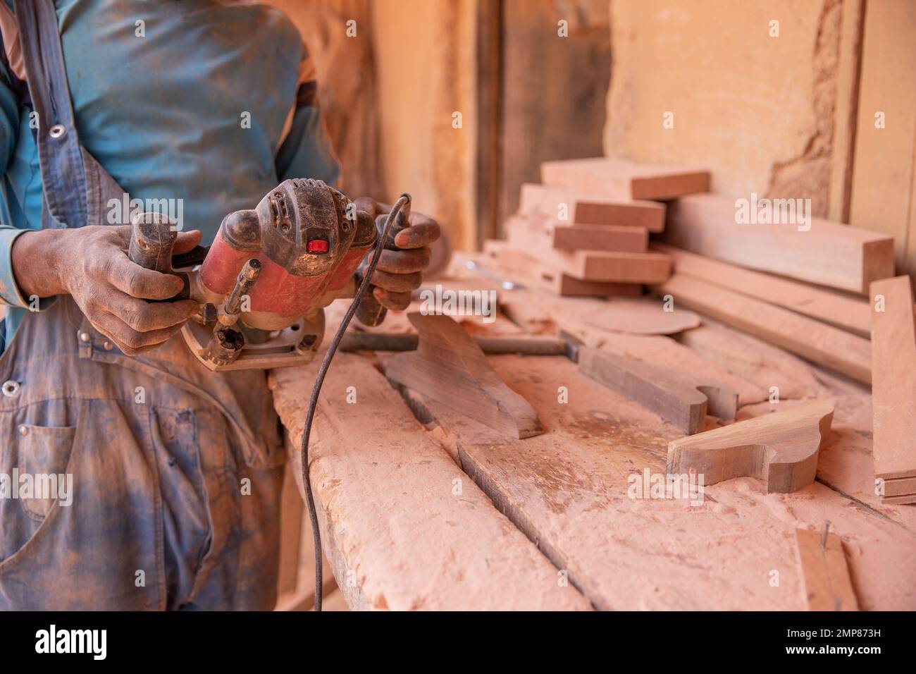 Primo piano di una levigatrice tenuta da un falegname africano sul lavoro Foto Stock