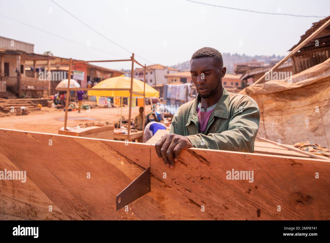 Un falegname taglia una tavola con una sega a mano nel suo laboratorio in Africa. Foto Stock