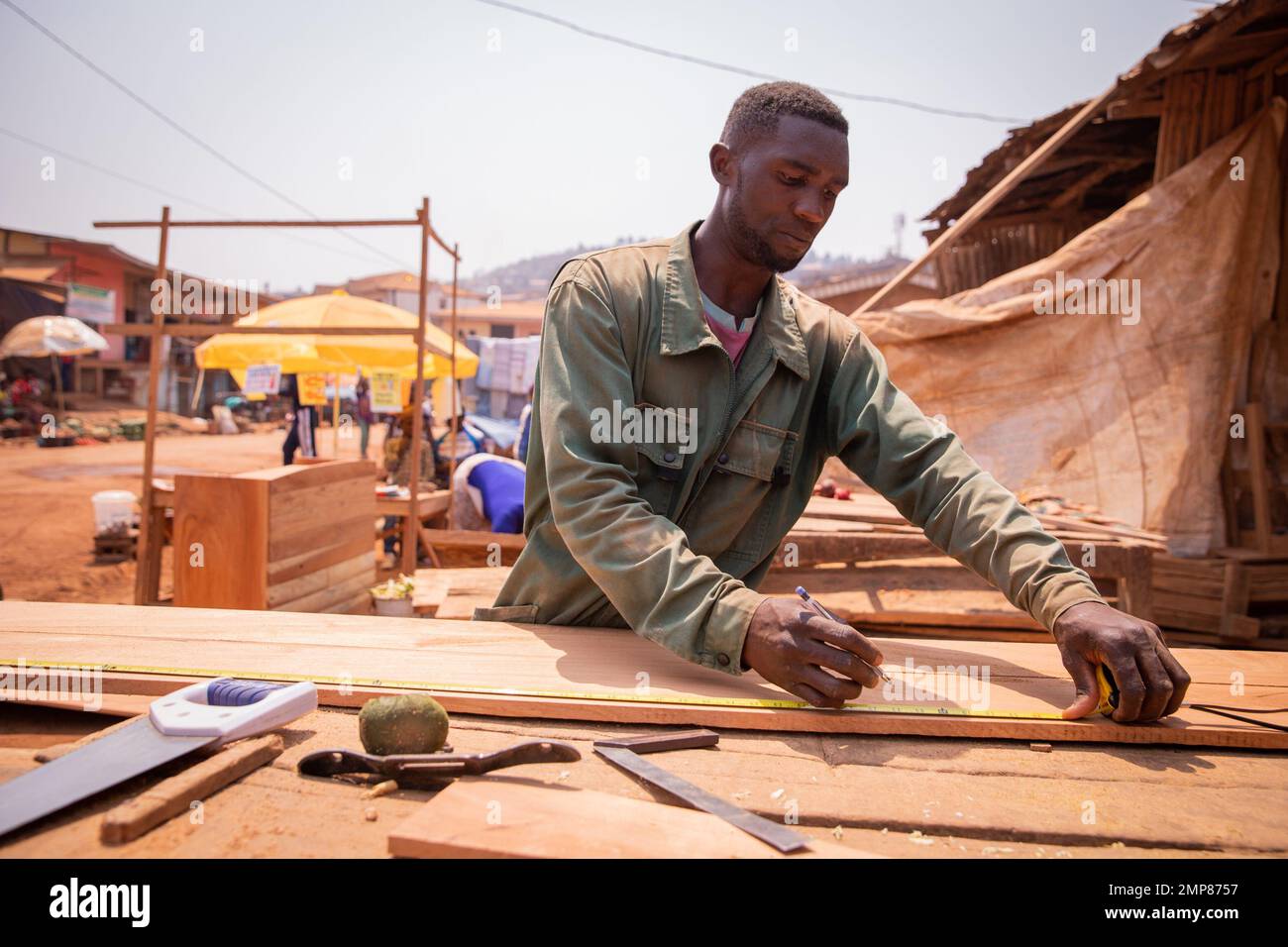 Un falegname africano che prende le misure mentre fa un pezzo di mobilia. Foto Stock