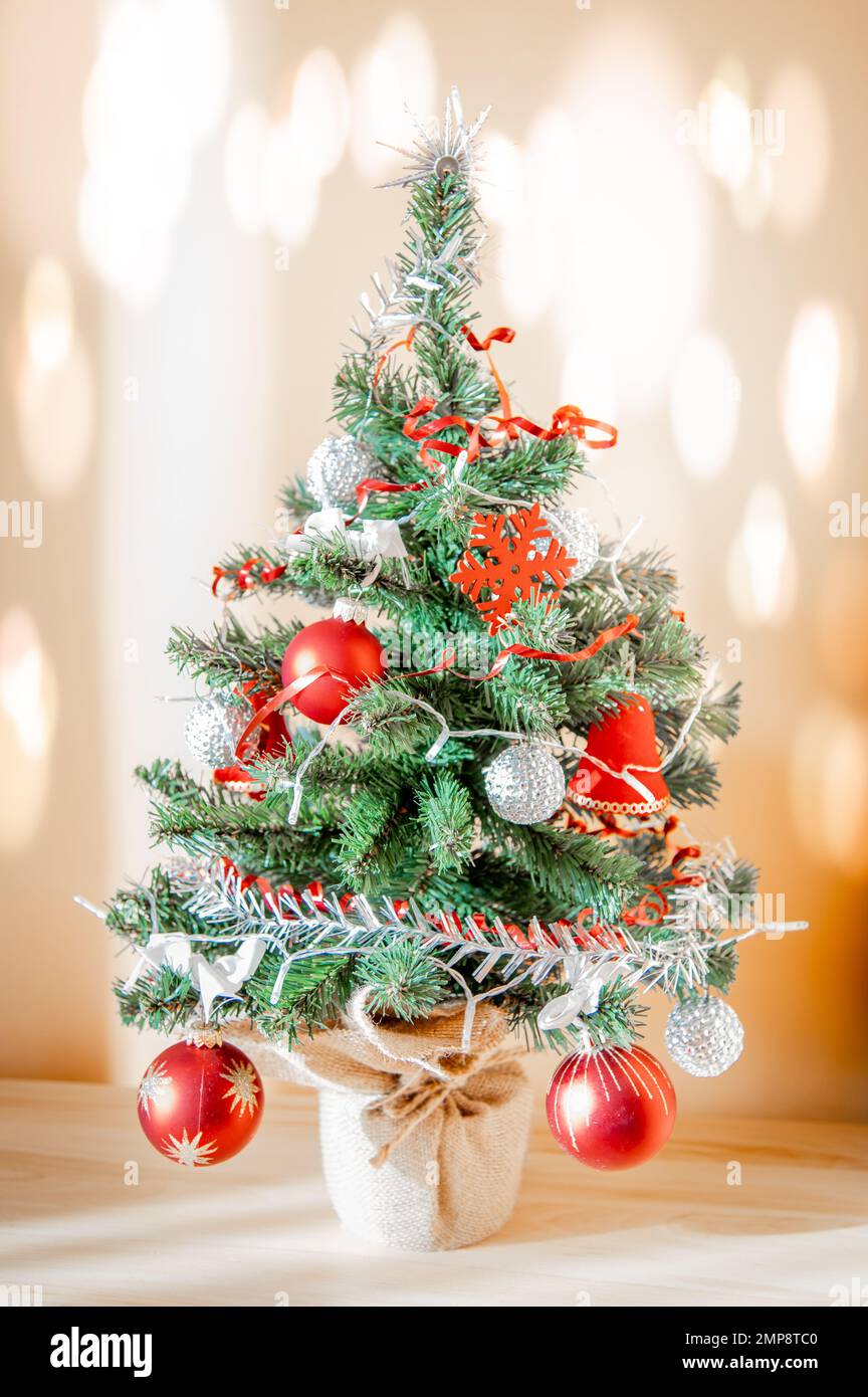 Piccolo albero di Natale decorato con pallina rossa e ornamenti d'argento.  Effetti di luce sulla parete Foto stock - Alamy
