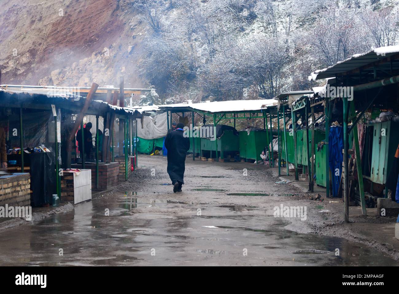 Mercato di stallo sulla strada nella campagna Tagikistan vicino a Nurek. Tajik locale persona a piedi nel freddo in Asia centrale. Foto Stock