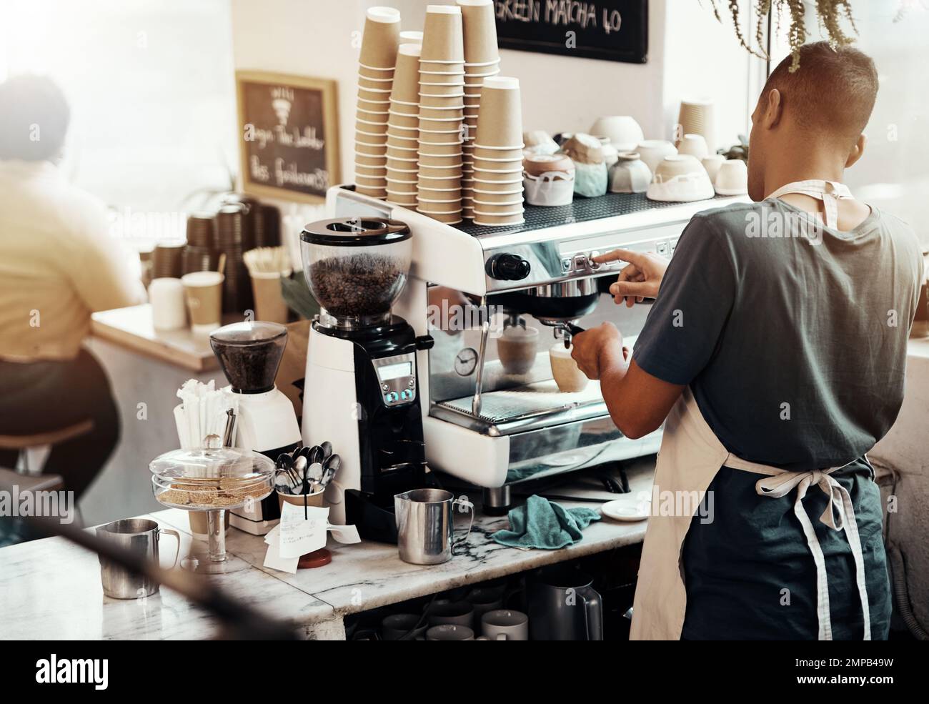 Caffè barista, uomo e servitore alla macchina da caffè per preparare l'espresso, quest'ultimo o cappuccino. Vista sul retro, cameriere e addetto alla caffetteria che vi hanno versato la caffeina Foto Stock