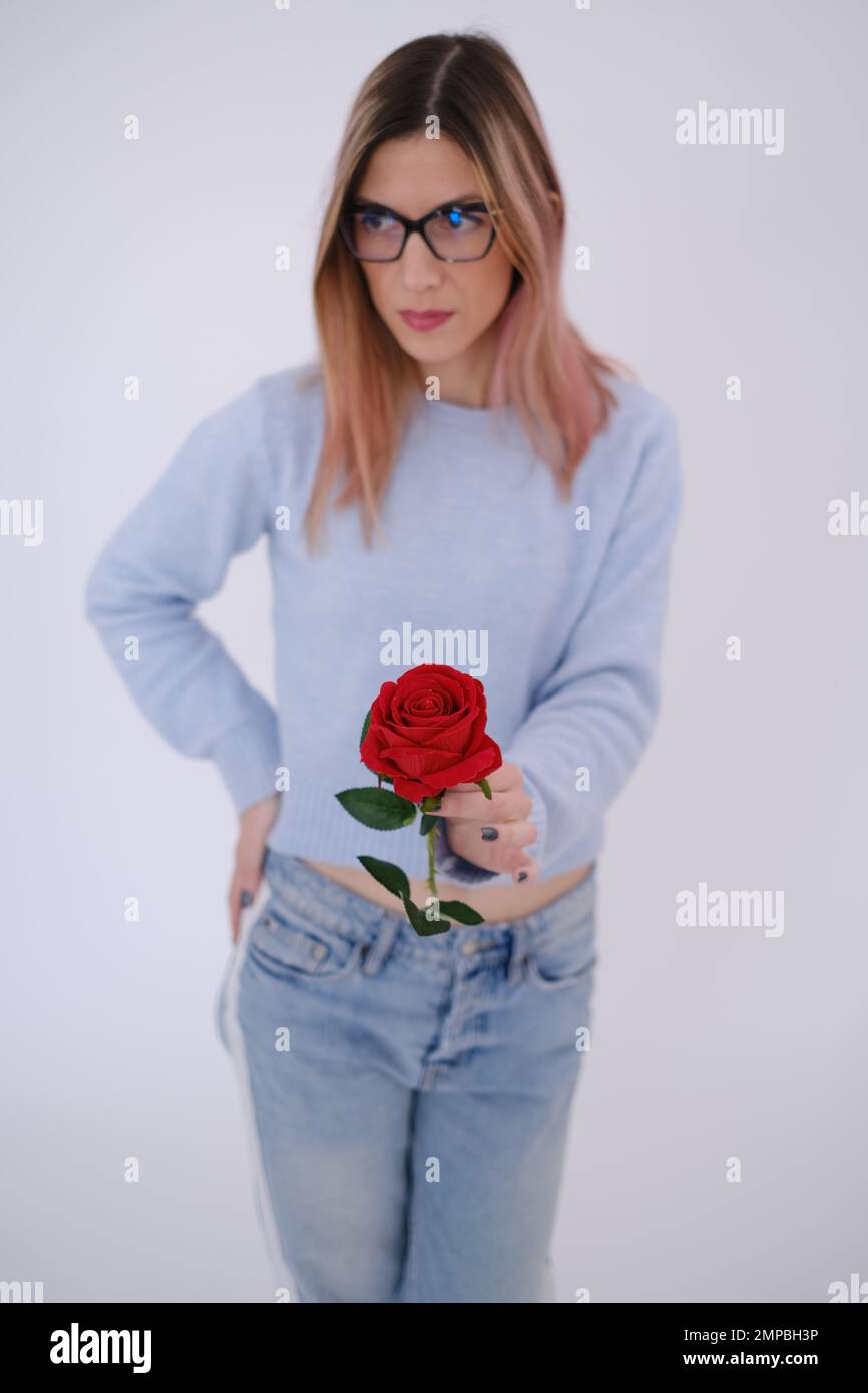 Giovane donna attraente che tiene e dà via una rosa. Concetto di amore. Amore di sé Foto Stock