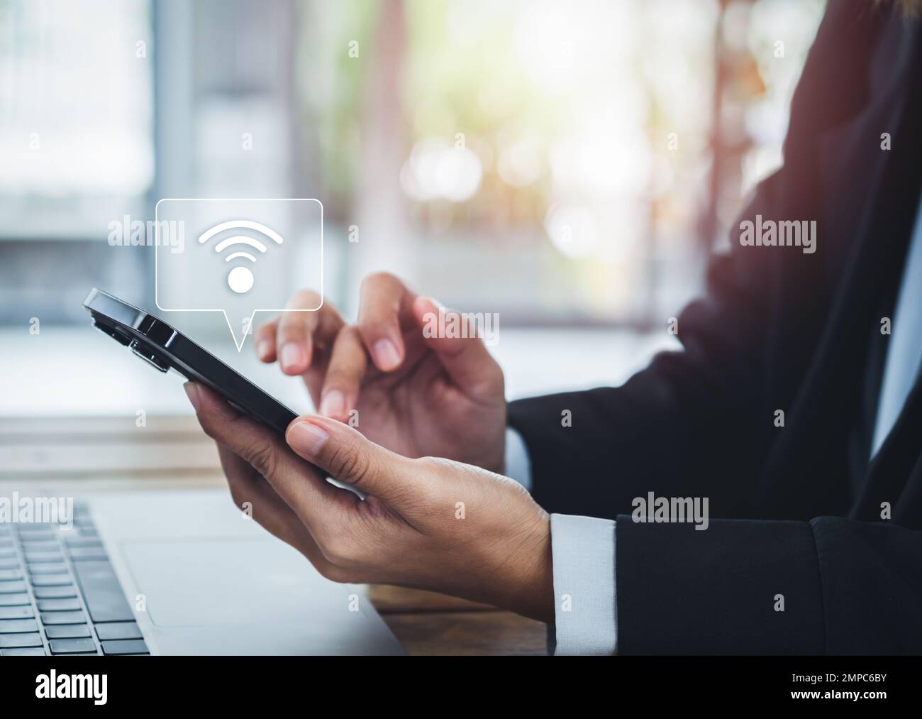 Condividi il wifi con uno smartphone. L'icona di condivisione viene visualizzata sul telefono cellulare in attesa da parte di persone in tuta, condividendo la connessione wifi per lavorare con lapto Foto Stock