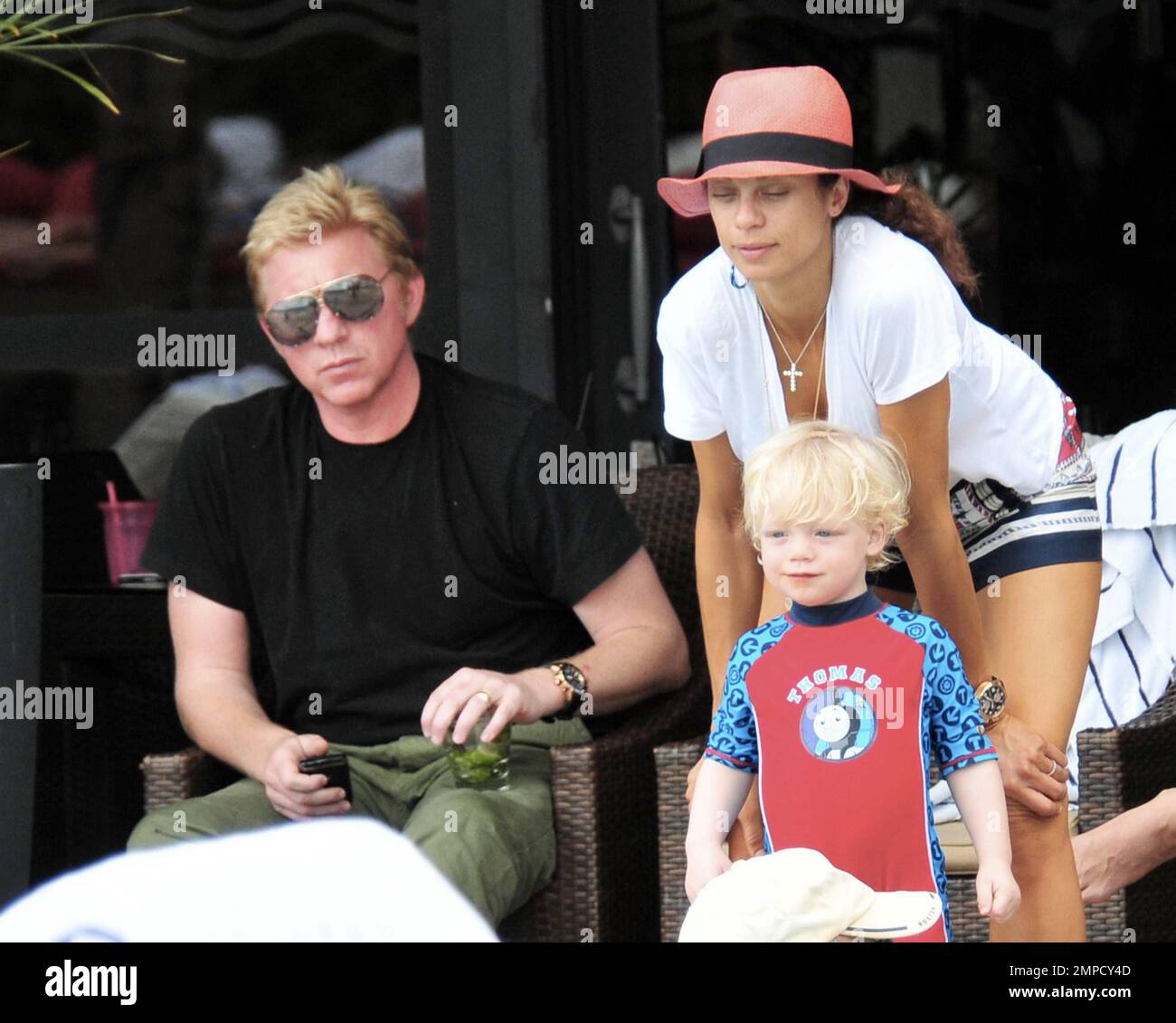 Boris Becker e sua moglie Lily sono stati visti godendo mojitos mentre si rilassavano in piscina con gli amici in un hotel a South Beach. Dopo aver trascorso diversi giorni sotto il sole di Miami, Boris sembrava un po' rosso sul viso, segni di una possibile scottatura del sole. Lily indossava un cappello color salmone con una parte superiore bianca e pantaloncini con motivi floreali sopra il bikini. Il figlio adorabile Amadeus di 2 anni è stato visto giocare in piscina mentre la mamma lo guardava. Ad un certo punto Lily ha letto un libro ad Amadeus mentre si è seduto sul suo grembo. Miami, Florida. 6th aprile 2012. Foto Stock