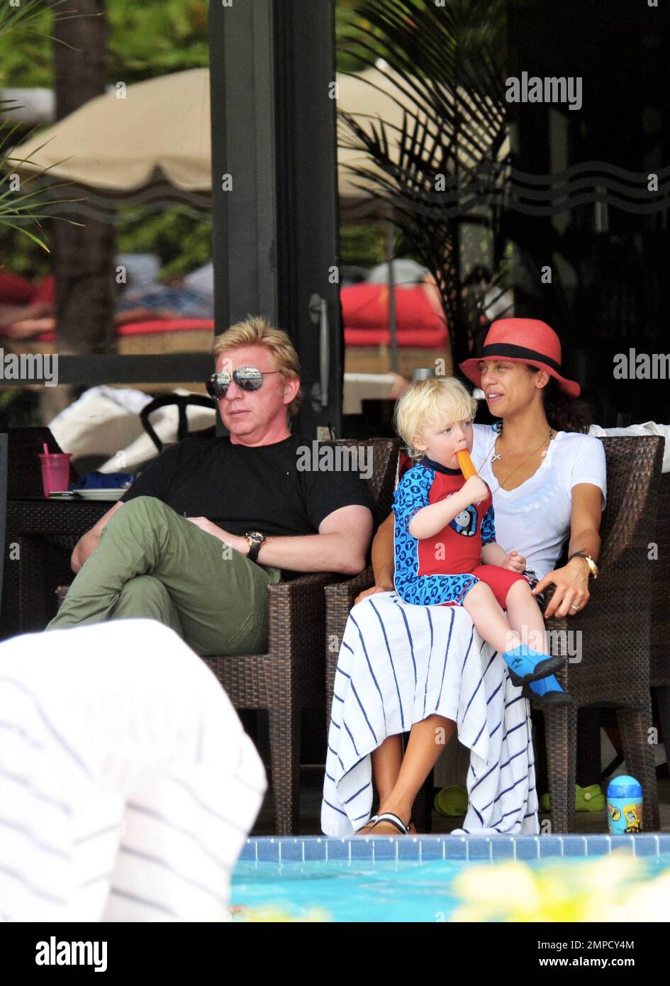 Boris Becker e sua moglie Lily sono stati visti godendo mojitos mentre si rilassavano in piscina con gli amici in un hotel a South Beach. Dopo aver trascorso diversi giorni sotto il sole di Miami, Boris sembrava un po' rosso sul viso, segni di una possibile scottatura del sole. Lily indossava un cappello color salmone con una parte superiore bianca e pantaloncini con motivi floreali sopra il bikini. Il figlio adorabile Amadeus di 2 anni è stato visto giocare in piscina mentre la mamma lo guardava. Ad un certo punto Lily ha letto un libro ad Amadeus mentre si è seduto sul suo grembo. Miami, Florida. 6th aprile 2012. Foto Stock