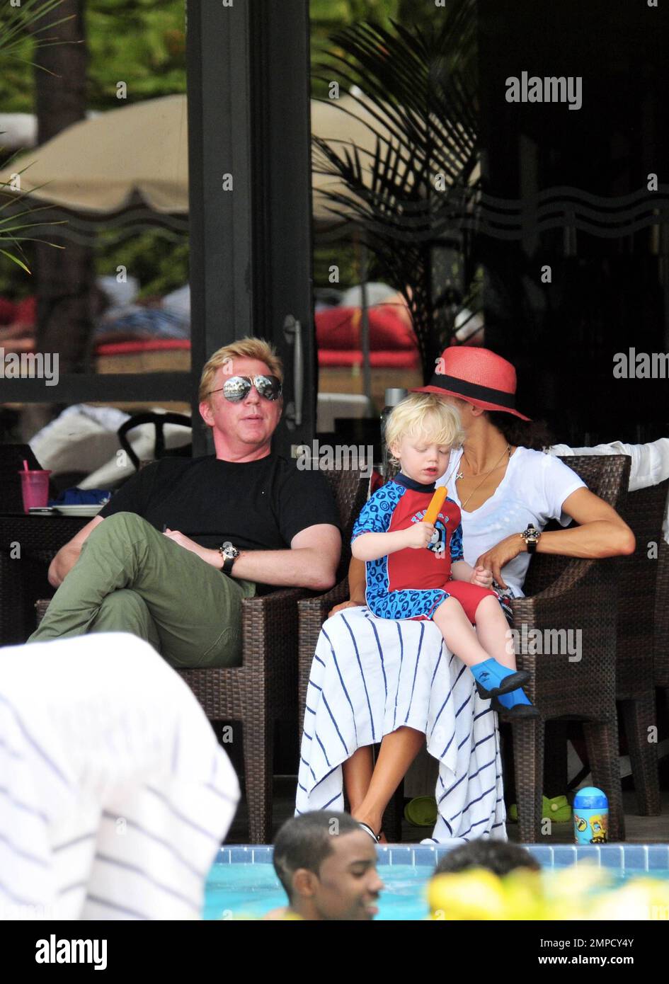 Boris Becker e sua moglie Lily sono stati visti godendo mojitos mentre si rilassavano in piscina con gli amici in un hotel a South Beach. Dopo aver trascorso diversi giorni sotto il sole di Miami, Boris sembrava un po' rosso sul viso, segni di una possibile scottatura del sole. Lily indossava un cappello color salmone con una parte superiore bianca e pantaloncini con motivi floreali sopra il bikini. Il figlio adorabile Amadeus di 2 anni è stato visto giocare in piscina mentre la mamma lo guardava. Ad un certo punto Lily ha letto un libro ad Amadeus mentre si è seduto sul suo grembo. Miami, Florida. 6th aprile 2012. Foto Stock