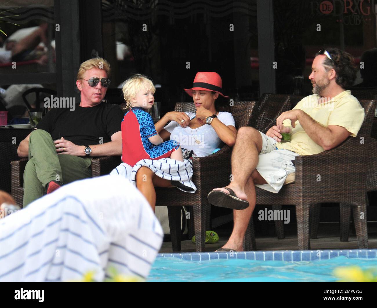 Boris Becker e sua moglie Lily sono stati visti godendo mojitos mentre si rilassavano in piscina con gli amici in un hotel a South Beach. Dopo aver trascorso diversi giorni sotto il sole di Miami, Boris sembrava un po' rosso sul viso, segni di una possibile scottatura del sole. Lily indossava un cappello color salmone con una parte superiore bianca e pantaloncini con motivi floreali sopra il bikini. Il figlio adorabile Amadeus di 2 anni è stato visto giocare in piscina mentre la mamma lo guardava. Ad un certo punto Lily ha letto un libro ad Amadeus mentre si è seduto sul suo grembo. Miami, Florida. 6th aprile 2012. Foto Stock