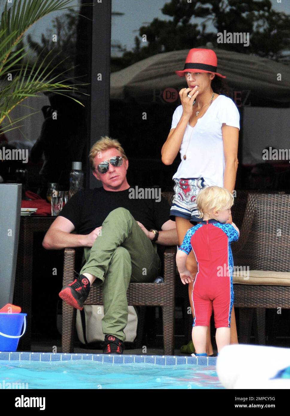 Boris Becker e sua moglie Lily sono stati visti godendo mojitos mentre si rilassavano in piscina con gli amici in un hotel a South Beach. Dopo aver trascorso diversi giorni sotto il sole di Miami, Boris sembrava un po' rosso sul viso, segni di una possibile scottatura del sole. Lily indossava un cappello color salmone con una parte superiore bianca e pantaloncini con motivi floreali sopra il bikini. Il figlio adorabile Amadeus di 2 anni è stato visto giocare in piscina mentre la mamma lo guardava. Ad un certo punto Lily ha letto un libro ad Amadeus mentre si è seduto sul suo grembo. Miami, Florida. 6th aprile 2012. Foto Stock