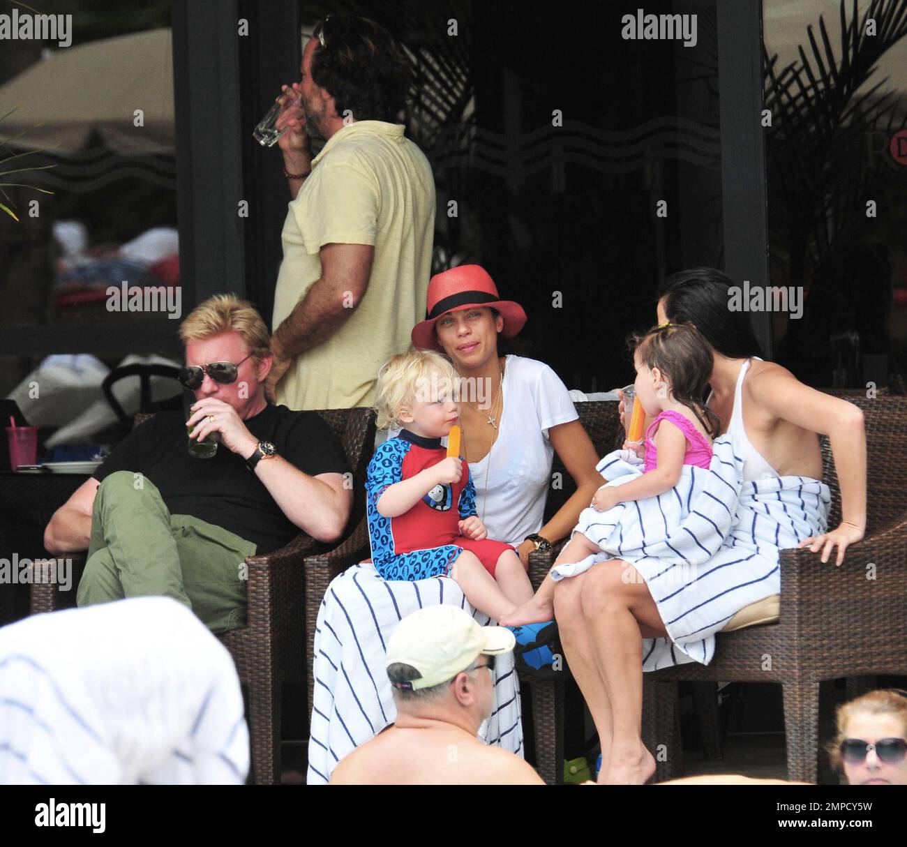 Boris Becker e sua moglie Lily sono stati visti godendo mojitos mentre si rilassavano in piscina con gli amici in un hotel a South Beach. Dopo aver trascorso diversi giorni sotto il sole di Miami, Boris sembrava un po' rosso sul viso, segni di una possibile scottatura del sole. Lily indossava un cappello color salmone con una parte superiore bianca e pantaloncini con motivi floreali sopra il bikini. Il figlio adorabile Amadeus di 2 anni è stato visto giocare in piscina mentre la mamma lo guardava. Ad un certo punto Lily ha letto un libro ad Amadeus mentre si è seduto sul suo grembo. Miami, Florida. 6th aprile 2012. . Foto Stock