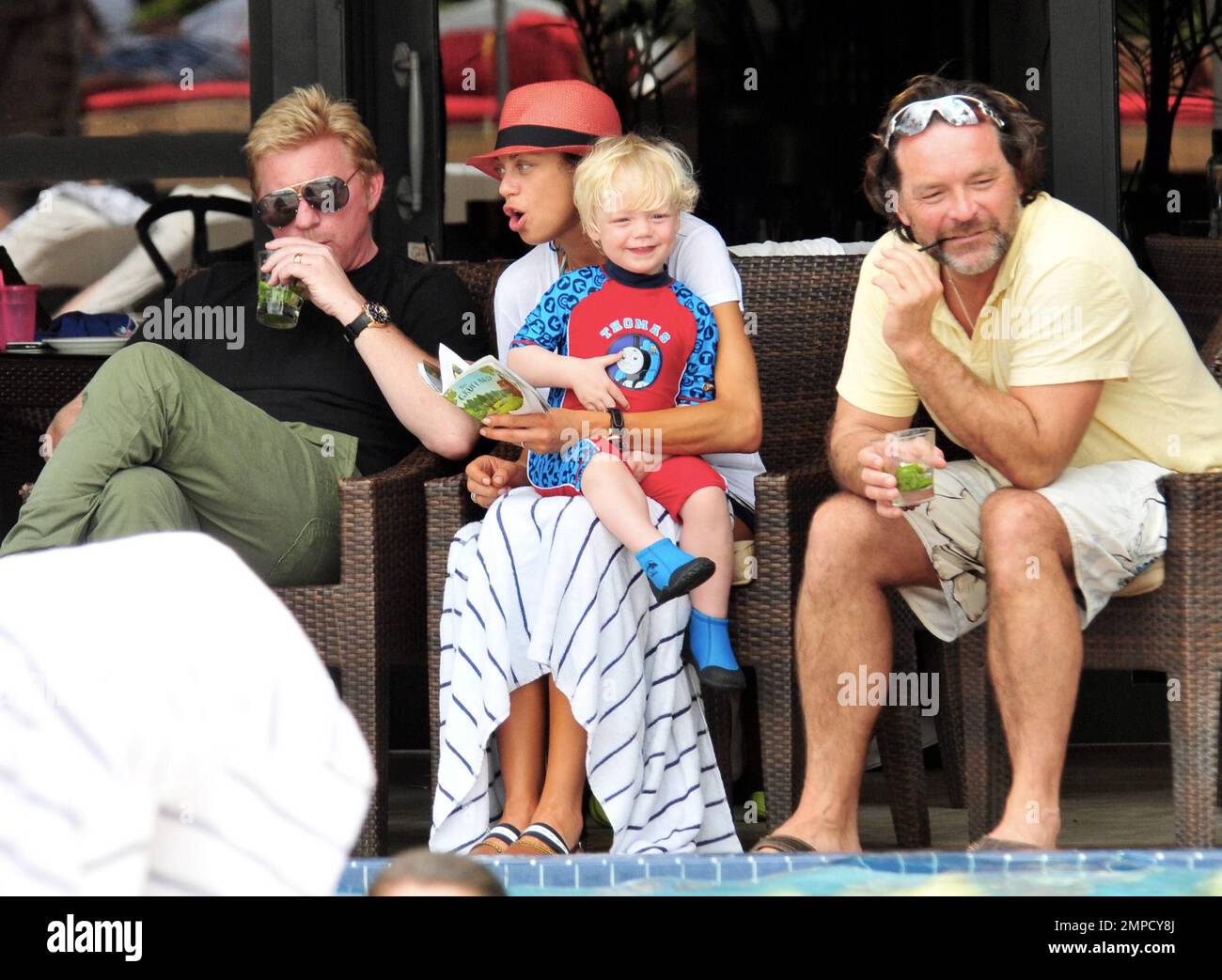 Boris Becker e sua moglie Lily sono stati visti godendo mojitos mentre si rilassavano in piscina con gli amici in un hotel a South Beach. Dopo aver trascorso diversi giorni sotto il sole di Miami, Boris sembrava un po' rosso sul viso, segni di una possibile scottatura del sole. Lily indossava un cappello color salmone con una parte superiore bianca e pantaloncini con motivi floreali sopra il bikini. Il figlio adorabile Amadeus di 2 anni è stato visto giocare in piscina mentre la mamma lo guardava. Ad un certo punto Lily ha letto un libro ad Amadeus mentre si è seduto sul suo grembo. Miami, Florida. 6th aprile 2012. . Foto Stock